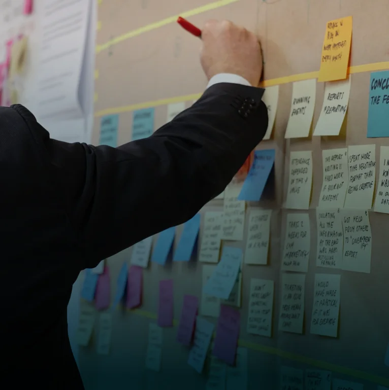 A strategist mapping a supply chain plan across a wall of sticky notes