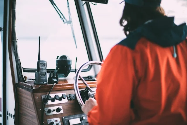 Crew member using a hand-held radio at the helm of a vessel