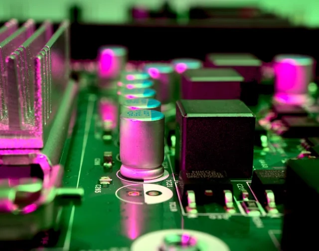 Close-up of a circuit board lit in magenta and green